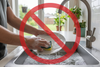 someone handwashing dishes, with a no sign overtop in front